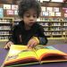 young boy practicing being a successful reader by reading at the library