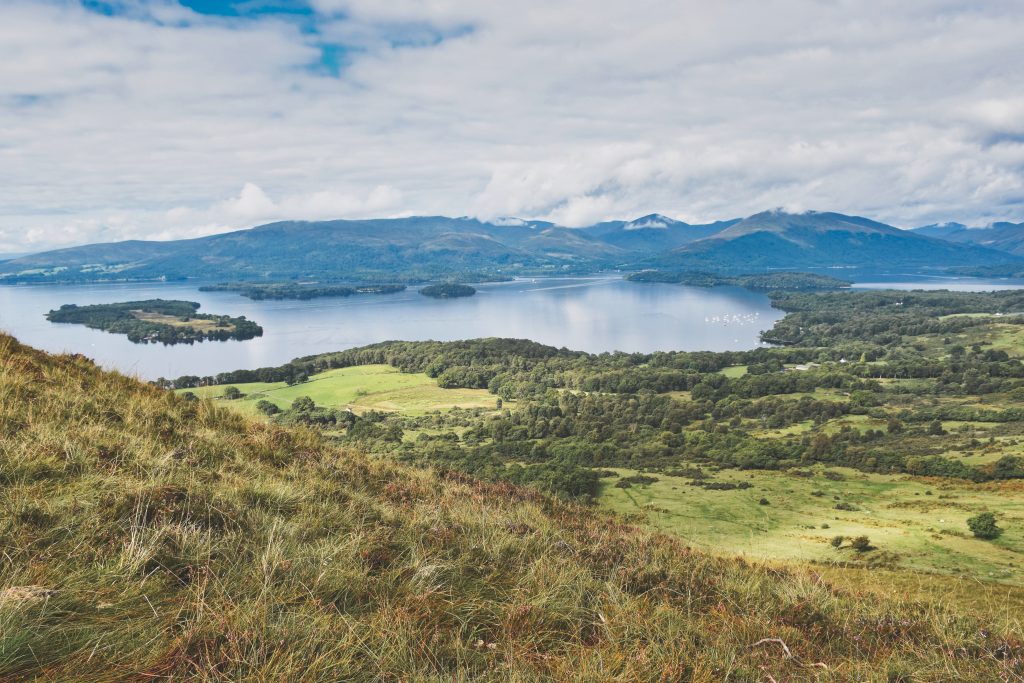 Loch Lomond in Scotland. Beautiful valley with a lake, green plains and mountains in the distance