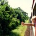 young child sticking their hand out a train window as it travels