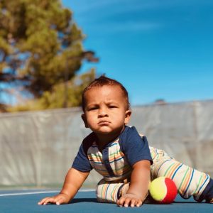 Little boy sitting outside with his hands out in front of him