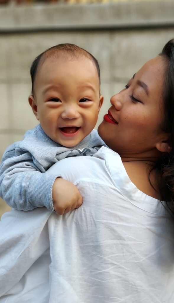 mom holding and smiling at her toddler while they travel  