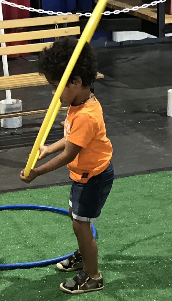 young toddler jumping with hula hoops indoors