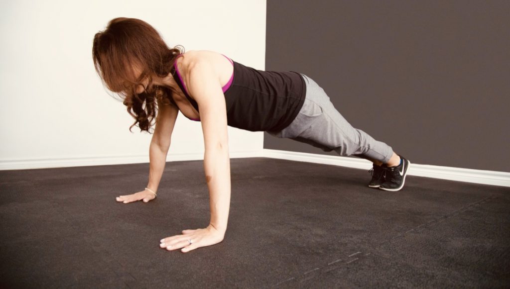 A woman holding a plank exercise on the floor