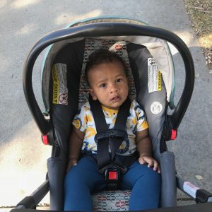 young child sitting in a stroller making eye contact with someone