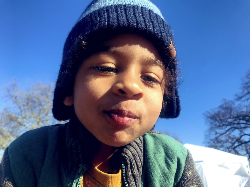 a little boy with blue hat on looking for fun outdoors