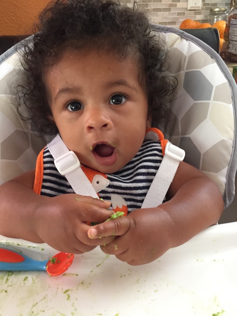 A baby eating soft finger foods while sitting in a high chair