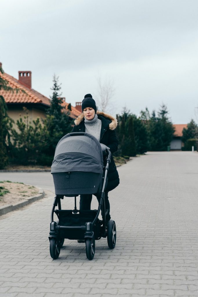 A stay-at-home mom outdoors in the cold pushing a baby stroller for exercise