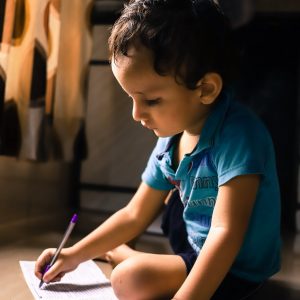 young boy sitting on the floor with a piece of paper and a pencil