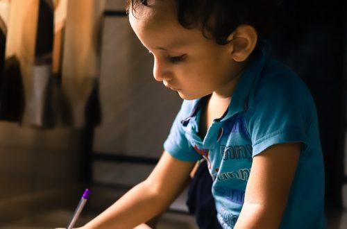 young boy sitting on the floor with a piece of paper and a pencil