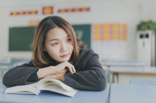 young girl thinking as she holds a book open