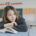 young girl thinking as she holds a book open