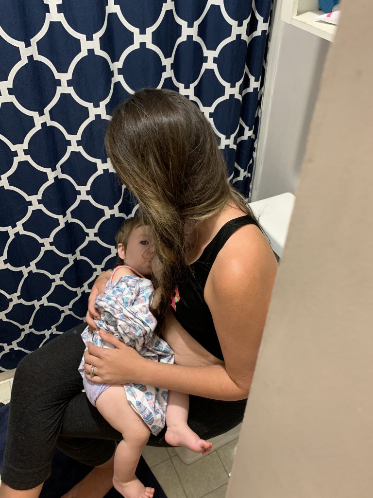 mom breastfeeding in bathroom with baby girl