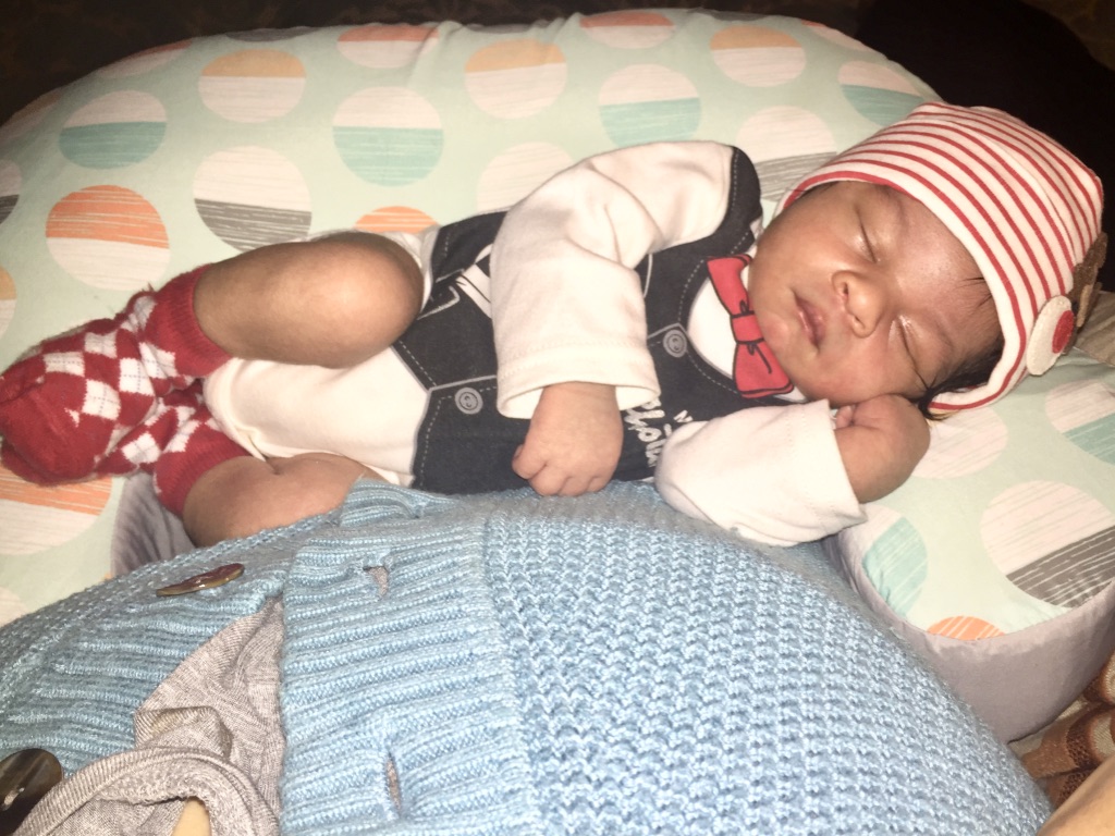 mom holding sleeping baby on breastfeeding pillow