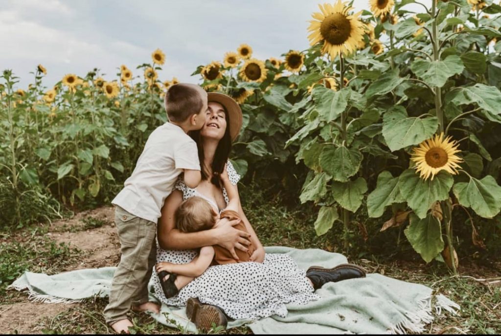 Timea breastfeeding in public in a field of sunflowers