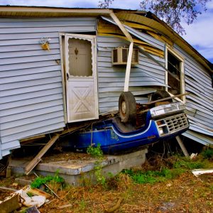 Hurricane damaged house on top of blue truck