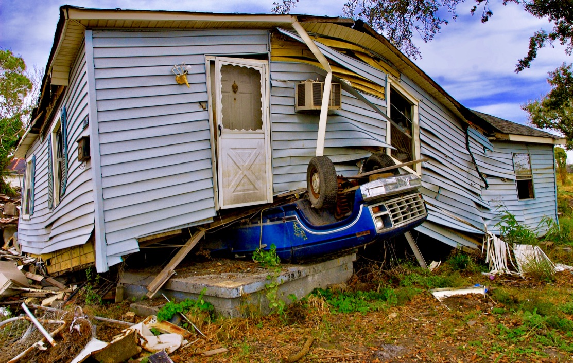 Hurricane damaged house on top of blue truck