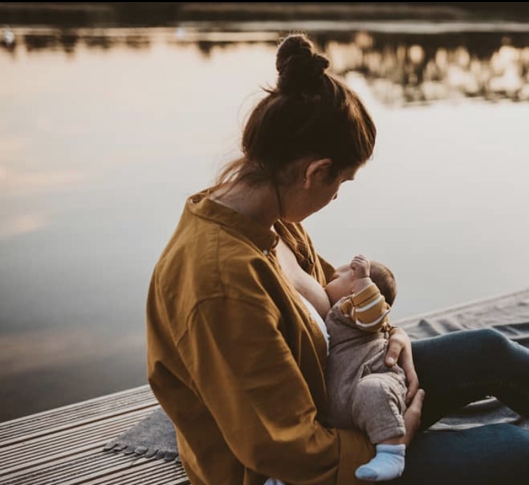 professional photo of mom breastfeeding her baby on boat dock