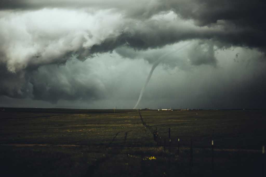 dark storm with tornado in the middle of a field