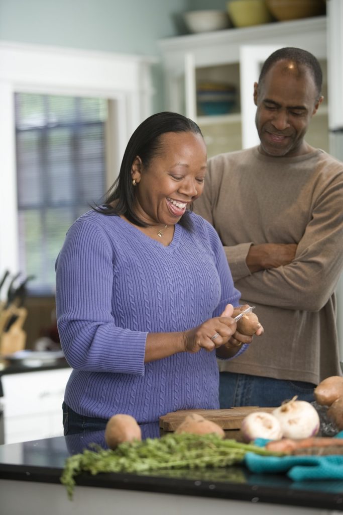 image from cdc of black man in a brown top and black woman in a purple top standing in their kitchen preparing a healthy meal