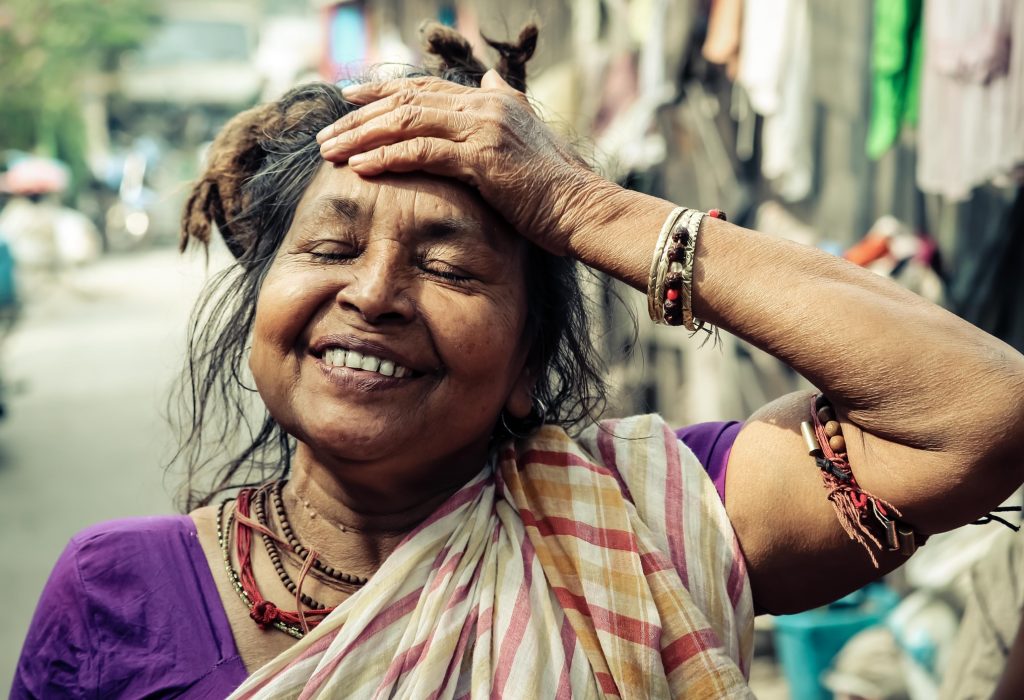 Lady from india with purple dress, smiling with her hand on her forehead