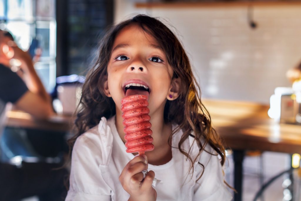 girl in white shirt eating a popsicle