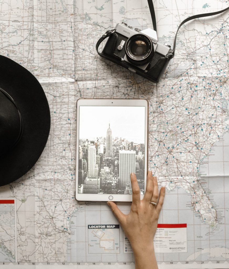 Person planning their US travel with a camera, map, and iPad.