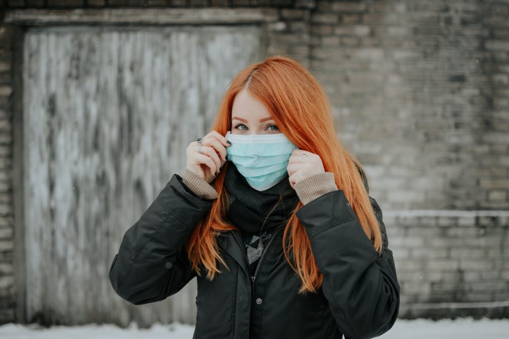 red hair woman with covid mask photographed outside while traveling