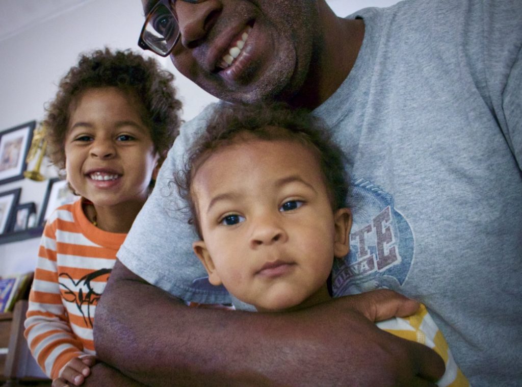 black dad with two kids taking a fun family photo