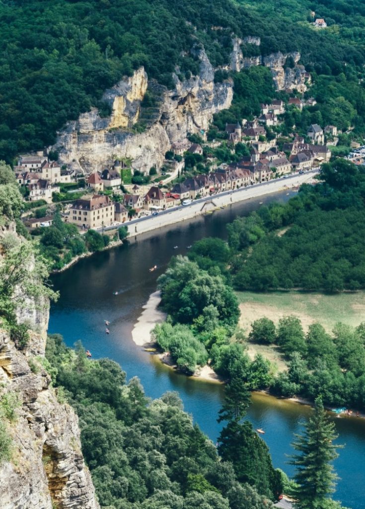 river running along a village in France with people kayaking in the water