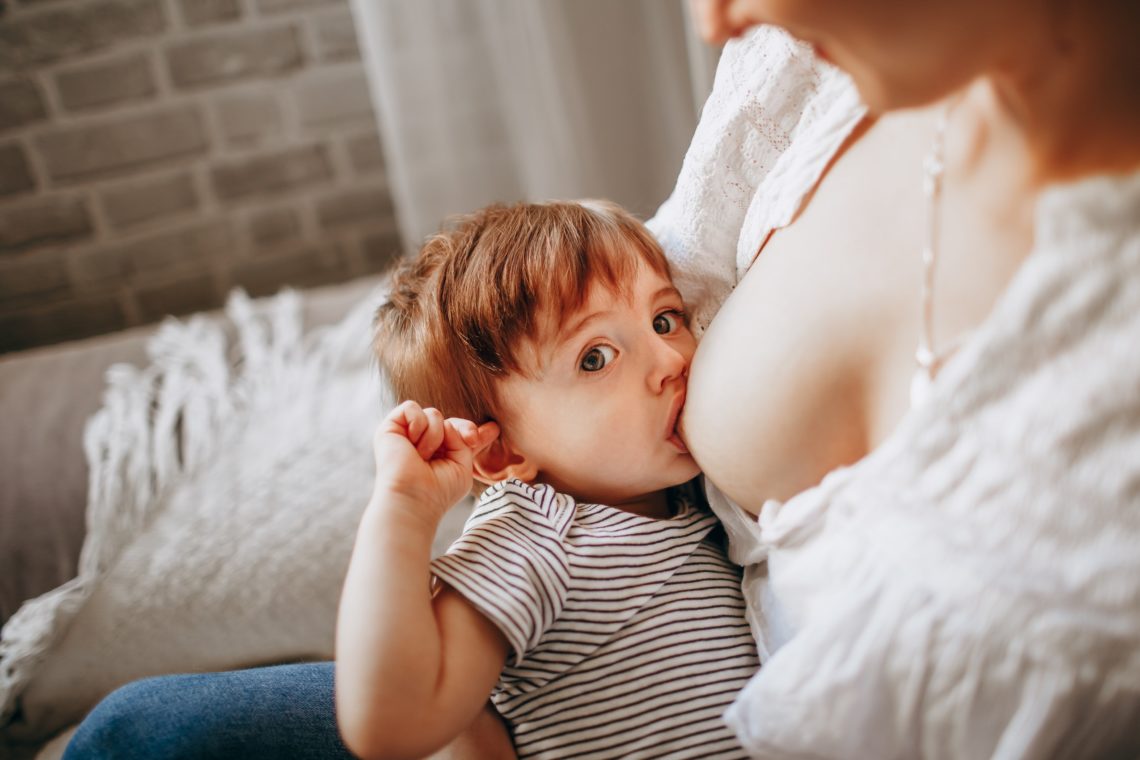 mom breastfeeding her toddler indoors