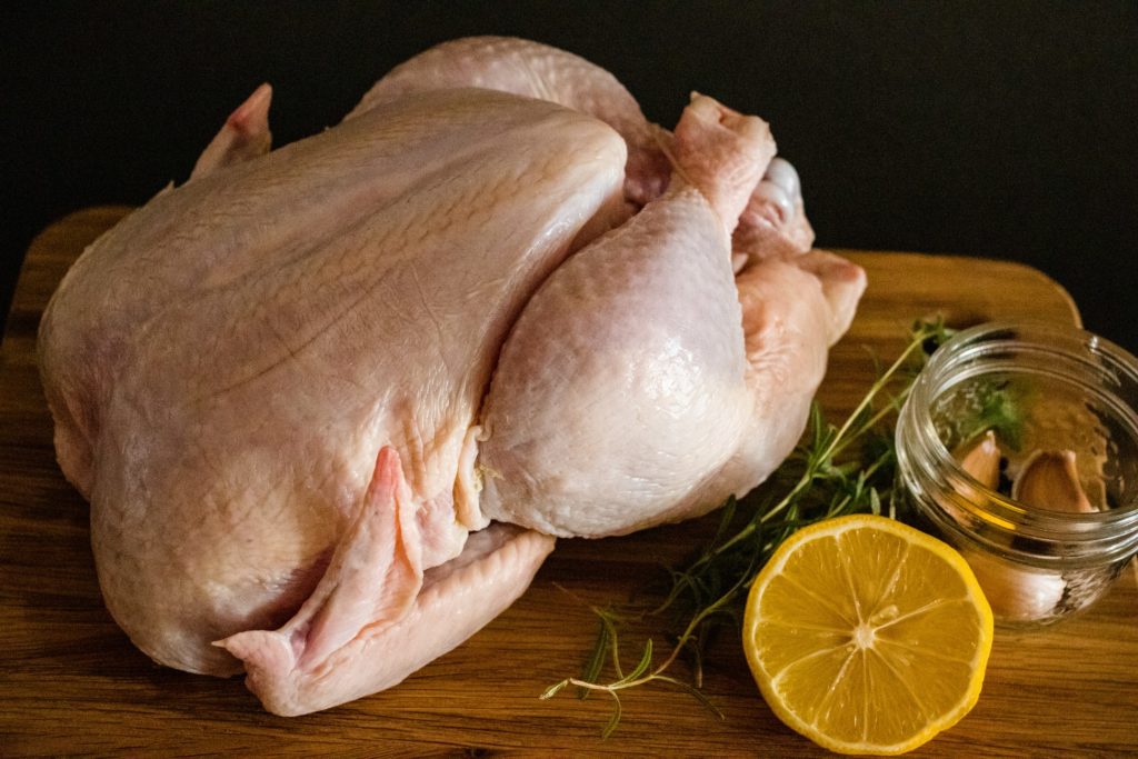 whole chicken on cutting board with type and lemon for chili