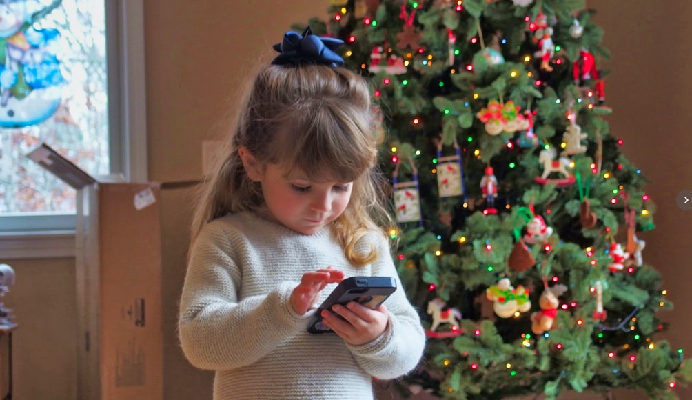 children with cellphone in front of tree