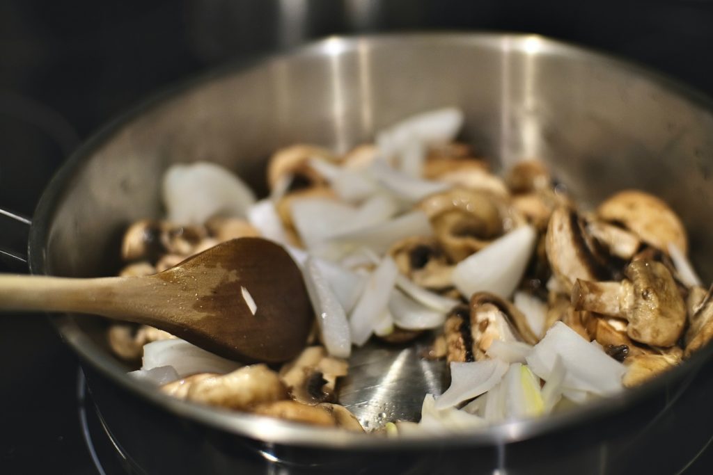 cooking mushrooms with onions and garlic in stainless steel sauté pan