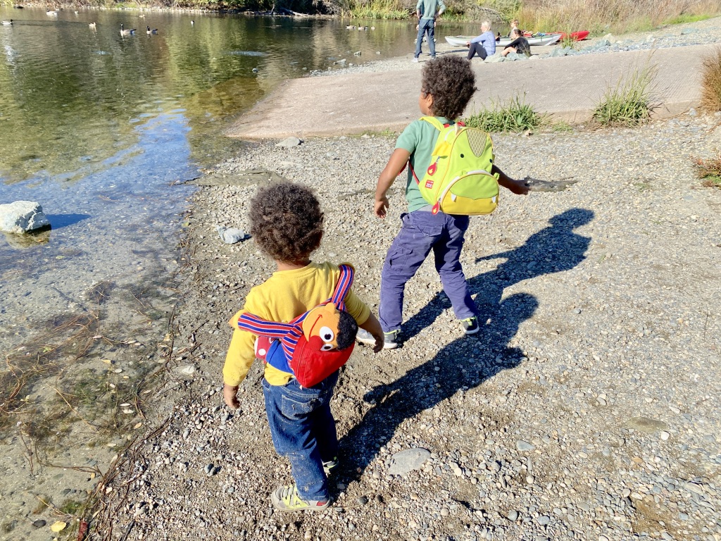 two kids outdoors playing by the water
